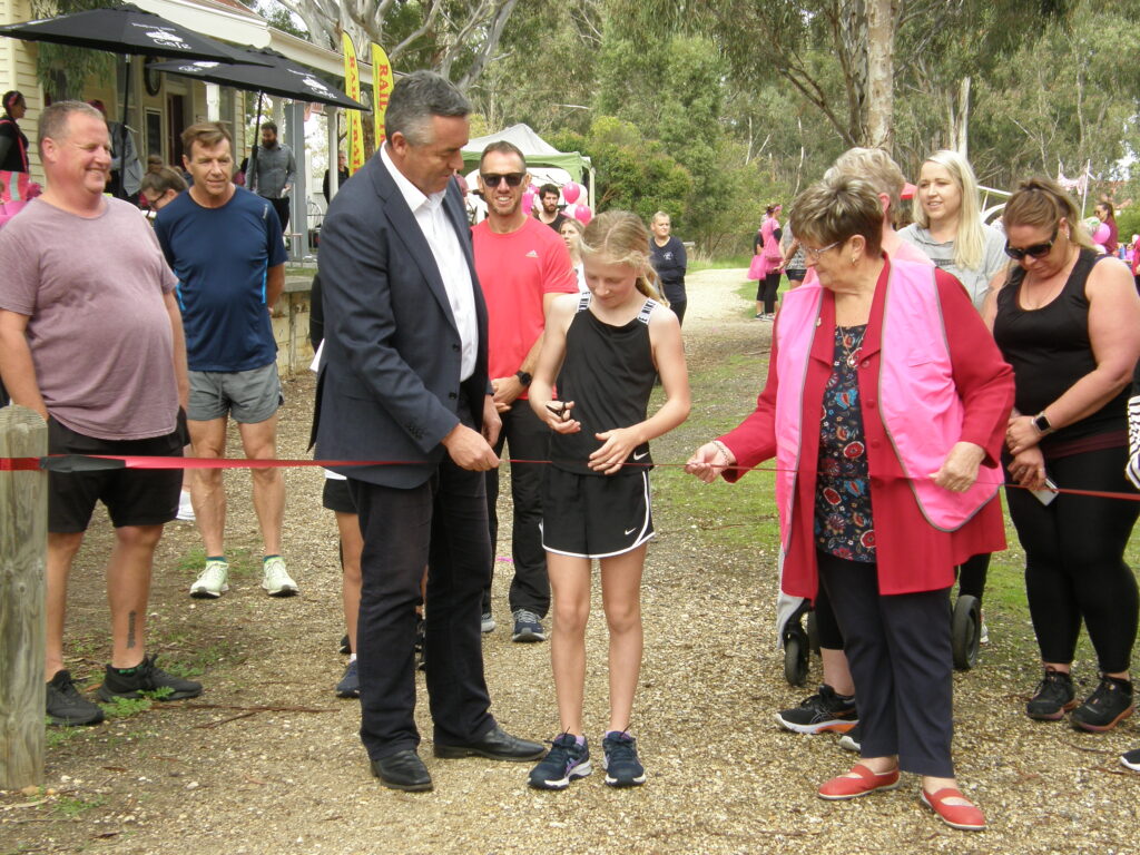 Young girl cuts ribbon alongside The Hon Darren Chester and Helen Hoppner, Chairperson of Gippsland Plains Rail Trail